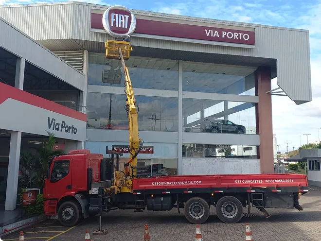 Caminhão Munck em operação na frente do galpão